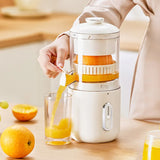 Person using a manual juicer to extract juice from oranges, with a glass of orange juice on a wooden surface.